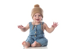 Cheerful baby sitting on a isolated floor with a wooled hat 