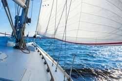 White sloop rigged yacht sailing in an open Baltic sea on a clear sunny day. A view from the deck to the bow, mast and sails. Estonia