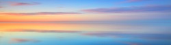 Picturesque panoramic scenery of the open Baltic sea at sunset. Symmetry reflections on the water, natural mirror. Breathtaking view. Winter seascape. Pure nature, seasons, climate change