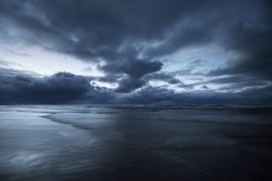 Dark storm sky above the Baltic sea, waves and water splashes. Dramatic cloudscape. Nature, environment, fickle weather, climate change. Atmospheric scenery. Panoramic view, long exposure