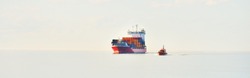 Large cargo container ship being led by the pilot boat. Piloting service. Unknown waters. Global communications, logistics, industry, freight transportation, nautical vessel, nautical route, port