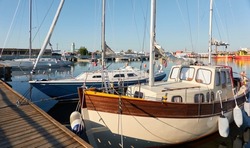 Elegant sailing boat (motorsailer) moored to a pier in a yacht marina. Transportation, pleasure craft, recreation, sport, leisure activity themes
