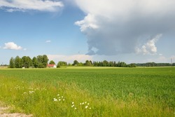 Green hills of a plowed agricultural field and forest. Idyllic summer rural scene. Dramatic sky after the rain. Pure nature, environnement, farm, countryside living, ecotourism. Panoramic view