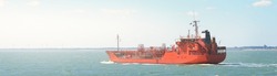 Red cargo tanker ship sailing next to the coast of Vlissingen, the Netherlands. Freight transportation, nautical vessel, fuel and power generation, logistics, industry, environment. Panoramic view