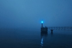 Panoramic view of Baltic sea at night. Port entrance, lighthouse. Thick fog, mist, blue light. Seascape. Monochrome scenery. Danger, safety concepts