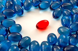 Pharmaceutical drugs and visual metaphor for leadership concept with pile of blue pills surround the red pill on white background