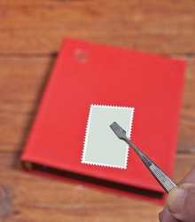 Postage stamps album and hand showing stamp with pincer