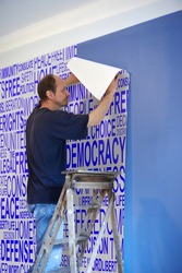 Man putting up wallpaper for Changing of scenery with a Background concept wordcloud of human rights
