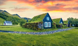 Typical view of turf-top houses in Icelandic countryside. Dramatic summer sunrise in Skogar village, south Iceland, Europe. Traveling concept background.