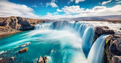 Sunny summer scene of Skjalfandafljot river, Iceland, Europe. Panoramic morning view of Godafoss, spectacular waterfall plunging over a curved, 12m-high precipice, with paths to various viewpoints. 