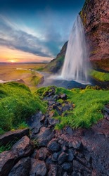 Popular tourist attraction - Seljalandsfoss waterfall, where tourists can walk behind the falling waters. Amazing summer scene of Iceland, Europe. Beauty of nature concept background.