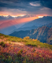 Сrack in the clouds at sunset. Unbelievable autumn view of mountain valley with Ushba peak. Colorful evening scene of Caucasus, Upper Svaneti, Georgia. Beauty of nature concept background.