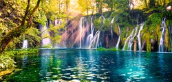 Last sunlight lights up the pure water waterfall on Plitvice National Park. Colorful spring panorama of green forest with blue lake. Great countryside view of Croatia, Europe. 