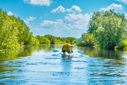 Couple at kayak trip on blue river landscape and green forest with trees blue water clouds sky