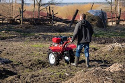 A farmer man plows the land with a cultivator. machinery cultivator for soil cultivation in the garden, motor cultivator.