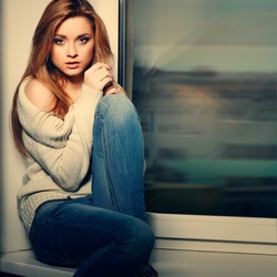 Beautiful long-haired girl, sitting on a window-sill