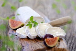 Goat cheese with figs and black olives on a wooden cutting board