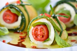 Caprese wrapped with fried zucchini slices, tied and knot with chives, marinated with olive oil and balsamic vinegar