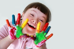 Cute little down syndrome girl with painted hands.