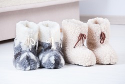 Two pair of natural woollen slippers on wooden floor