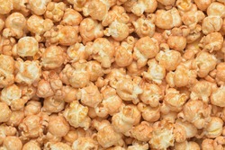 Heap of fresh yellow cooked caramel crunch popcorn background macro shot.