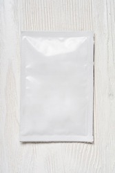 White blank paper sachet packet on wood table. Mock-up template for design.