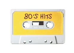 An old vintage cassette tape (obsolete music technology) with the handwritten text: 80's hits. White-grey plastic body and warm yellow label, isolated on white.
