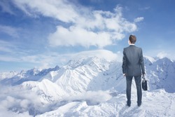 businessman with briefcase looking to winter mountains