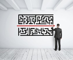 businessman drawing maze on white wall