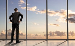 businessman standing in office and looking in sky