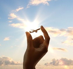 hand holding airplane on sky background