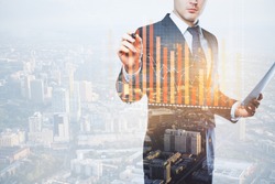 Young european businessman with document in hand drawing abstract business chart on city background with copy space. Finance concept. Double exposure