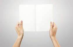 Female hands holding a blank white notebook. On a grey background