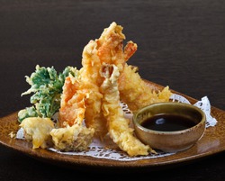 Tempura shrimps (deep fried shrimps) with soy sauce on wooden background. 