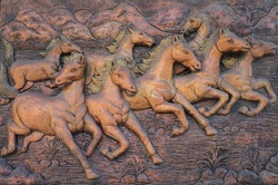 Low relief cement Thai style handcraft of horse on wall.