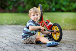 Little toddler boy repairing his first bike