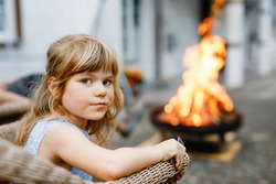 Little toddler girl girl roasting marshmallows on stick at bonfire. Child having fun at camp fire. Camping with children on backyard. Family leisure with kids at summer.