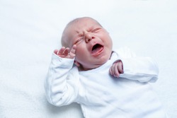 Crying newborn baby on changing table. Cute little girl or boy two weeks old. Dry and healthy body and skin concept. Baby nursery