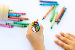 Close-up of child's hands with lots of colorful wax crayons pencils. Kid preparing school and nursery equipment and student stuff. Back to school. Education, school, learning concept.