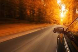 Close up of a car speeding on the empty, autum road with copy space