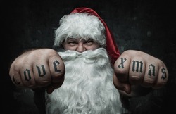 Funny angry Santa Claus showing fists with tattoo