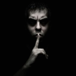 Evil man gesturing silence, quiet isolated on black background