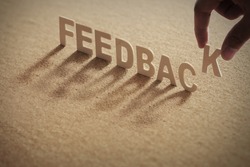 FEEDBACK wood word on compressed board,cork board with human's finger at K letter