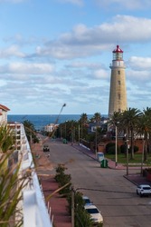 View from the balcony to a narrow street, a tall lighthouse and the ocean in Punta del Este, Uruguay