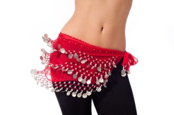 Action shot of the torso of a female belly dancer shaking her hips. She is dressed for rehearsing and practicing belly dance wearing a red coin belt and black leggings. Isolated on white.