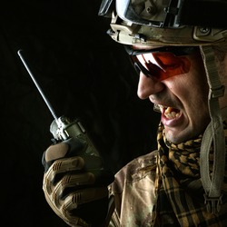 close up portrait of handsome military man. Macro shot on black background with portable radio transceiver