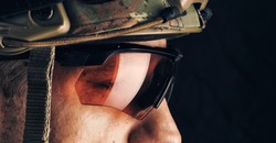 close up portrait of handsome military man in helmet and glasses. Macro shot on black background
