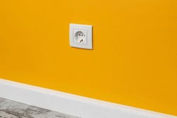 Yellow outlet installed on the white wall, side view.
