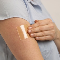 ATTRACTIVE HEALTHY YOUNG BLONDE WOMAN APPLYING TRANSPARENT NICOTINE PATCH TO ARM