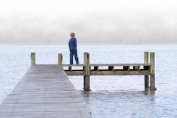 A young boy standing on a pier.